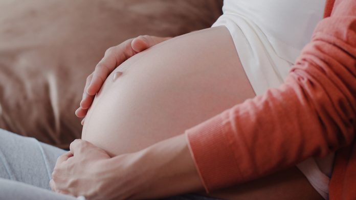 Young Asian Pregnant woman holding her belly talking with her ch